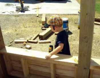 son helping to build a wooden pirate playhouse ship